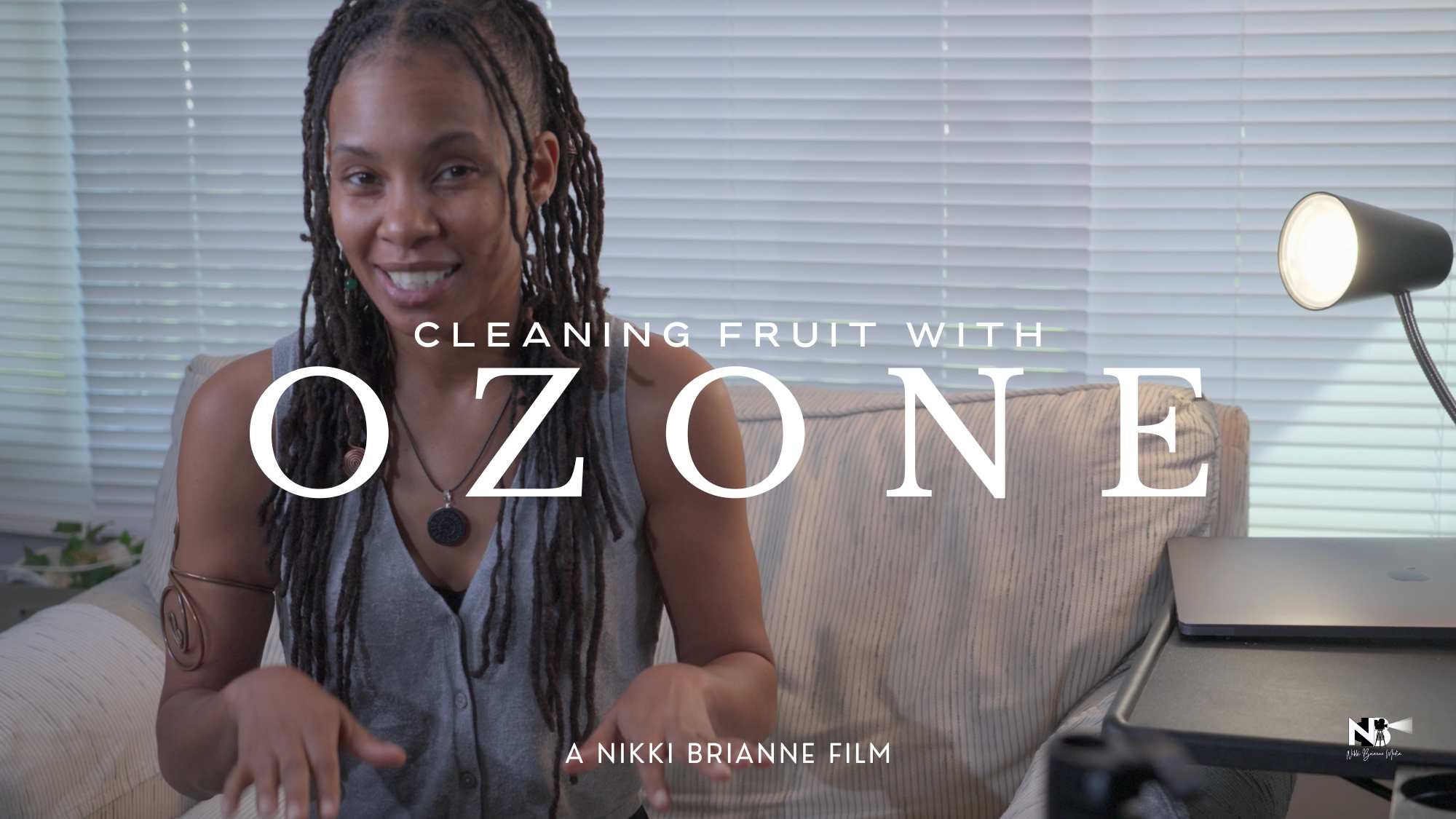 Nikki Brianne seated in front of the camera, explaining the benefits of cleaning fruit with ozone in an instructional video.